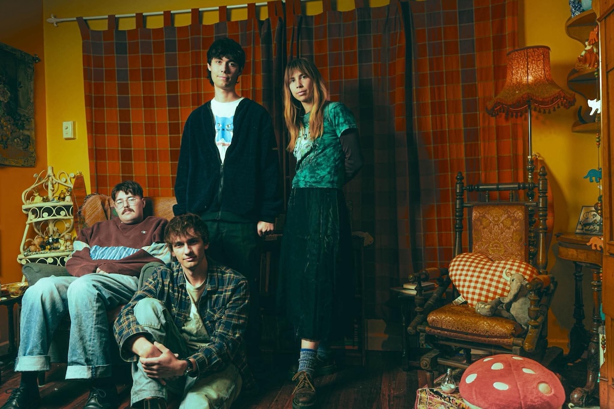 Promotional portrait of Australian indie pop band The Tullamarines posing together in a warm, vintage-style living room setting.